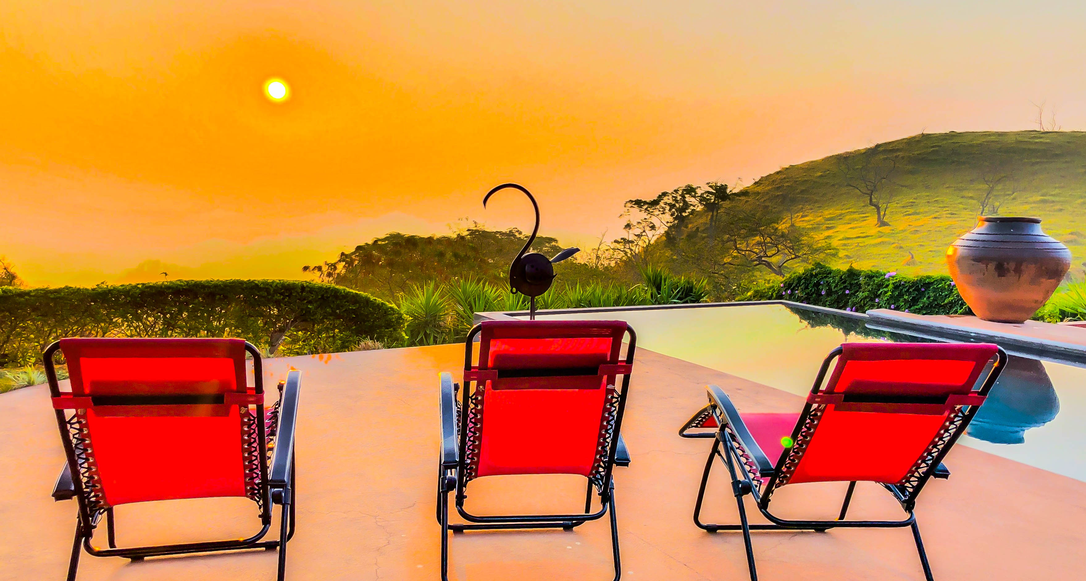Red lounge chairs overlooking a golden mountain sunset